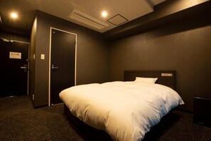 Une chambre d’hôtel avec un grand lit, un mur de couleur sombre et une porte dotée d’un interrupteur.