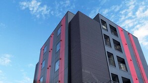 Een modern meerlaags gebouw met een opvallend architectonisch ontwerp, dat een combinatie van verticale en horizontale lijnen op de gevel toont.