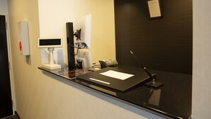 Een receptiebalie met een flatscreen, een telefoon en een notitieboekje.