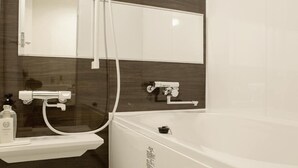 Een moderne badkamer met een ruime badkuip, een wastafel met spiegel en een douchekop.
