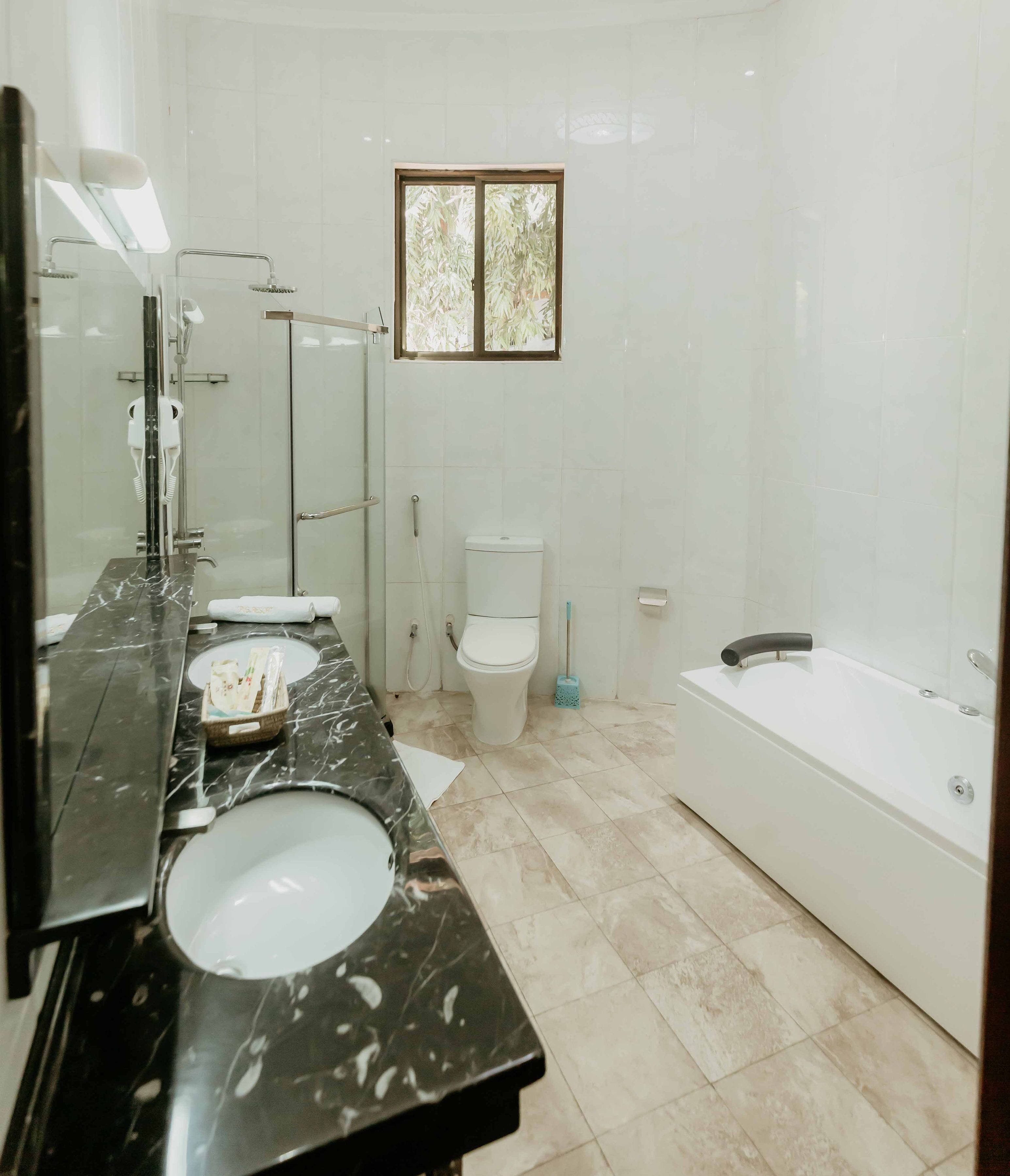 A modern bathroom with a long vanity, two sinks, a toilet, and a bathtub.