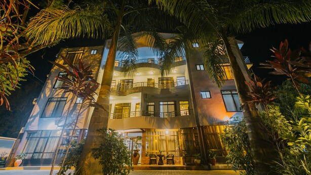 A multi-story hotel with balconies, large windows, and outdoor seating. - Panama Garden Resort (Moshi)
