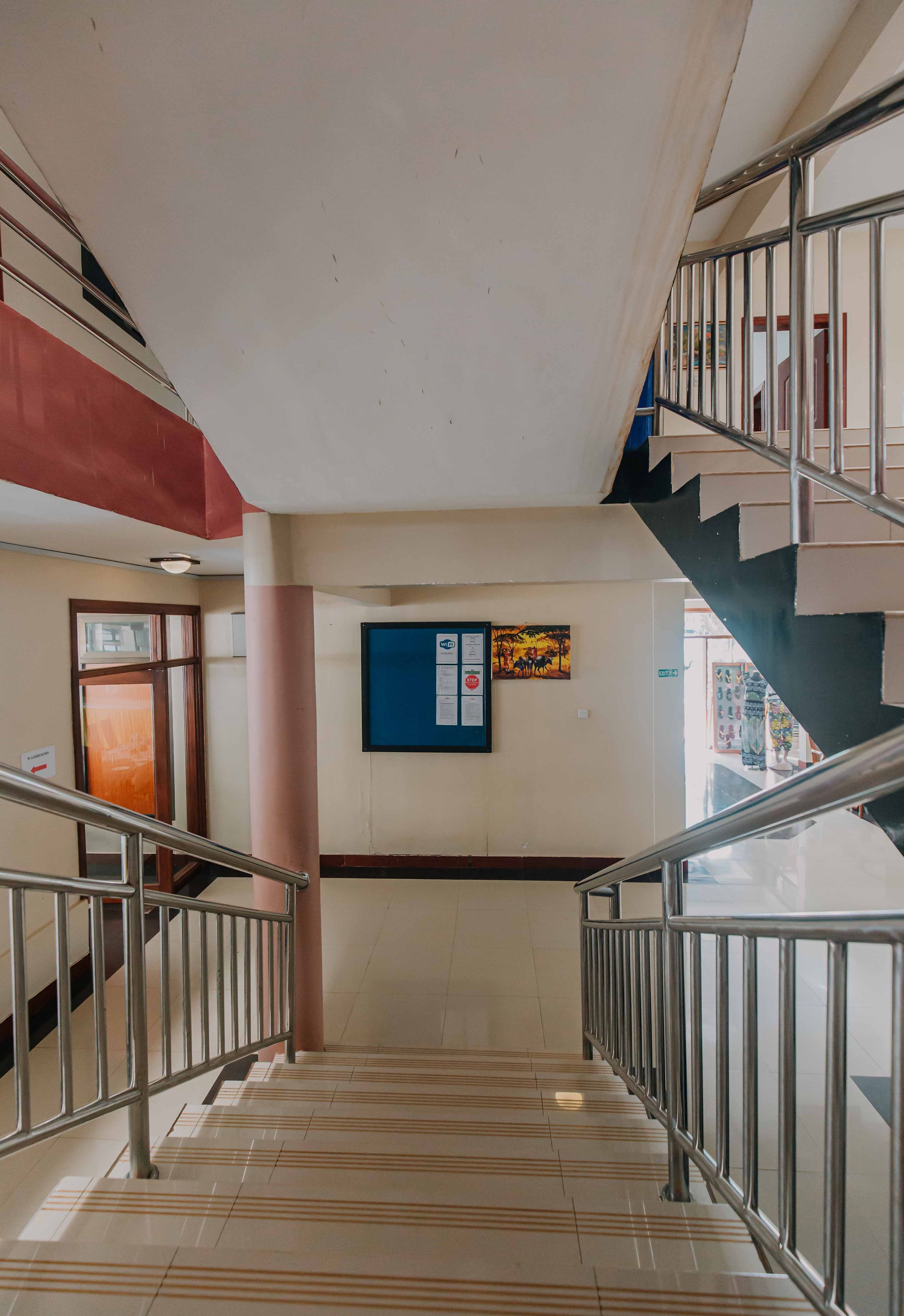 A staircase with metal railings, a tiled floor, and a wall with a framed picture and a bulletin board.