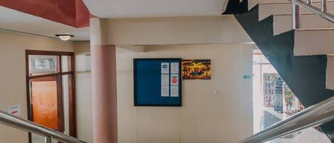 A staircase with metal railings, a tiled floor, and a wall with a framed picture and a bulletin board.