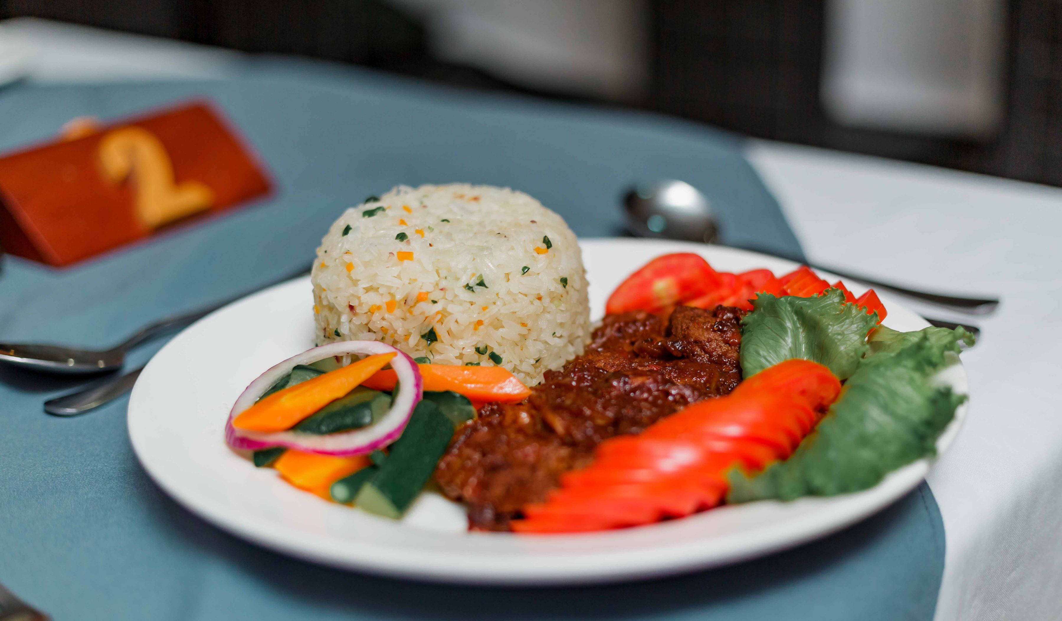 A plate of food with rice, vegetables, and meat, served on a white plate.