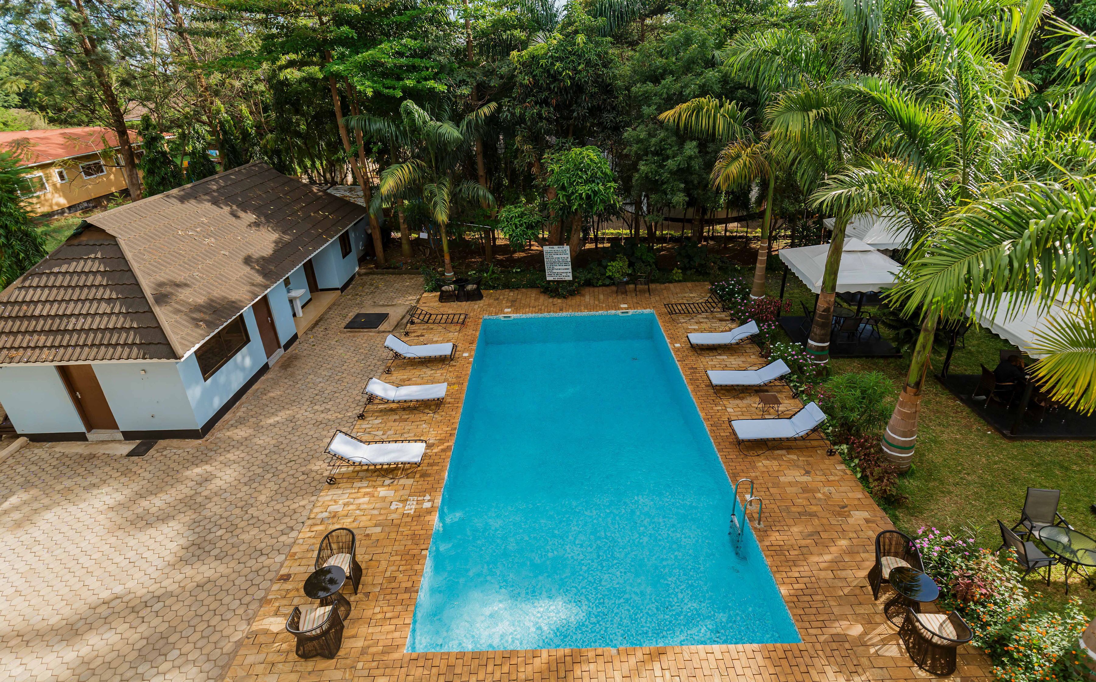 A rectangular swimming pool with lounge chairs and a small building with a tiled roof.