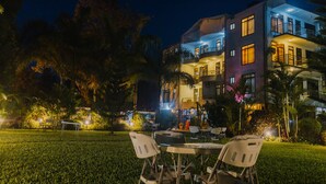 A multi-story hotel with outdoor seating and a well-lit garden area at night. - Panama Garden Resort (Moshi)