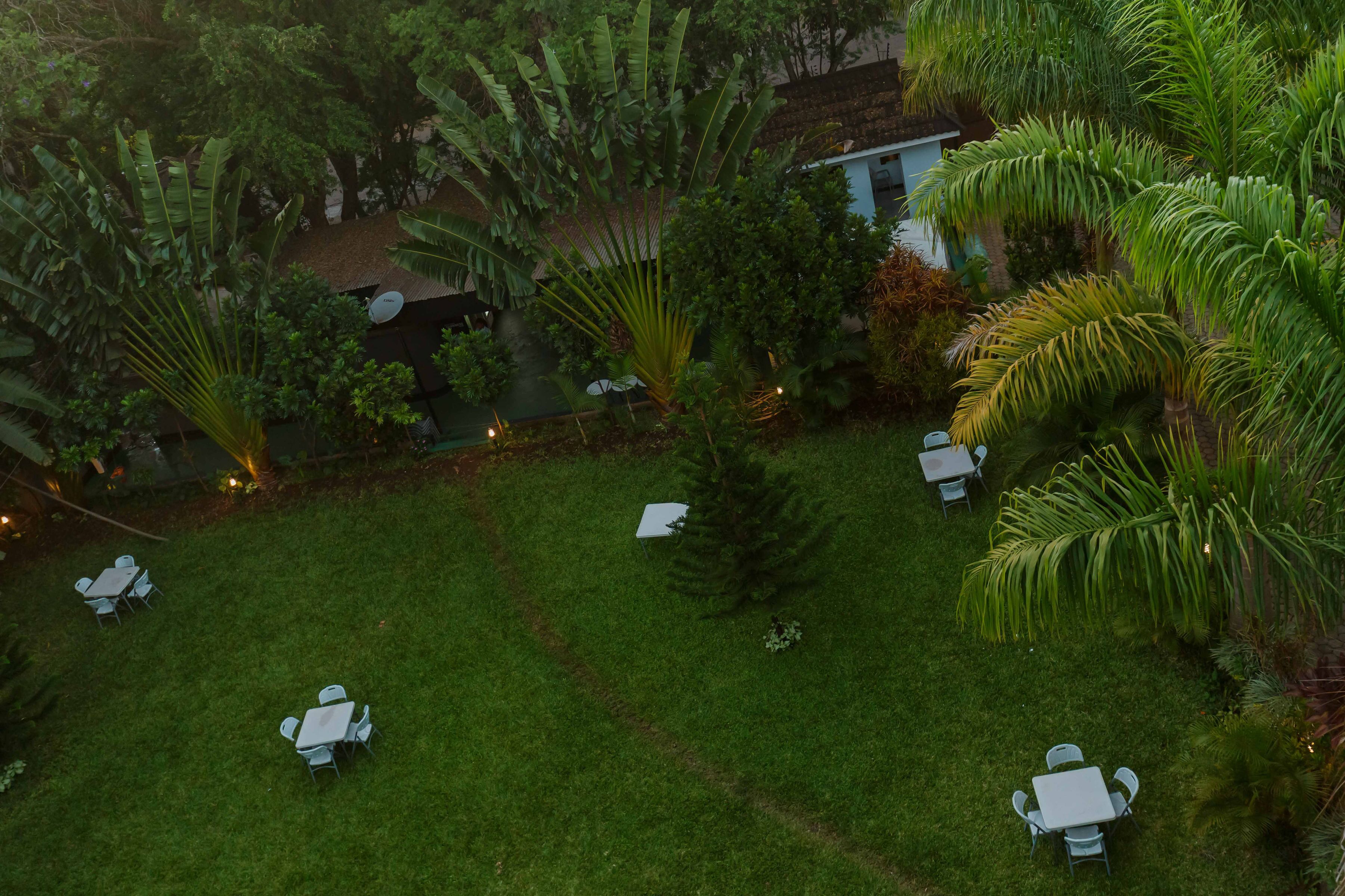 A lush garden with a dining area featuring white tables and chairs.