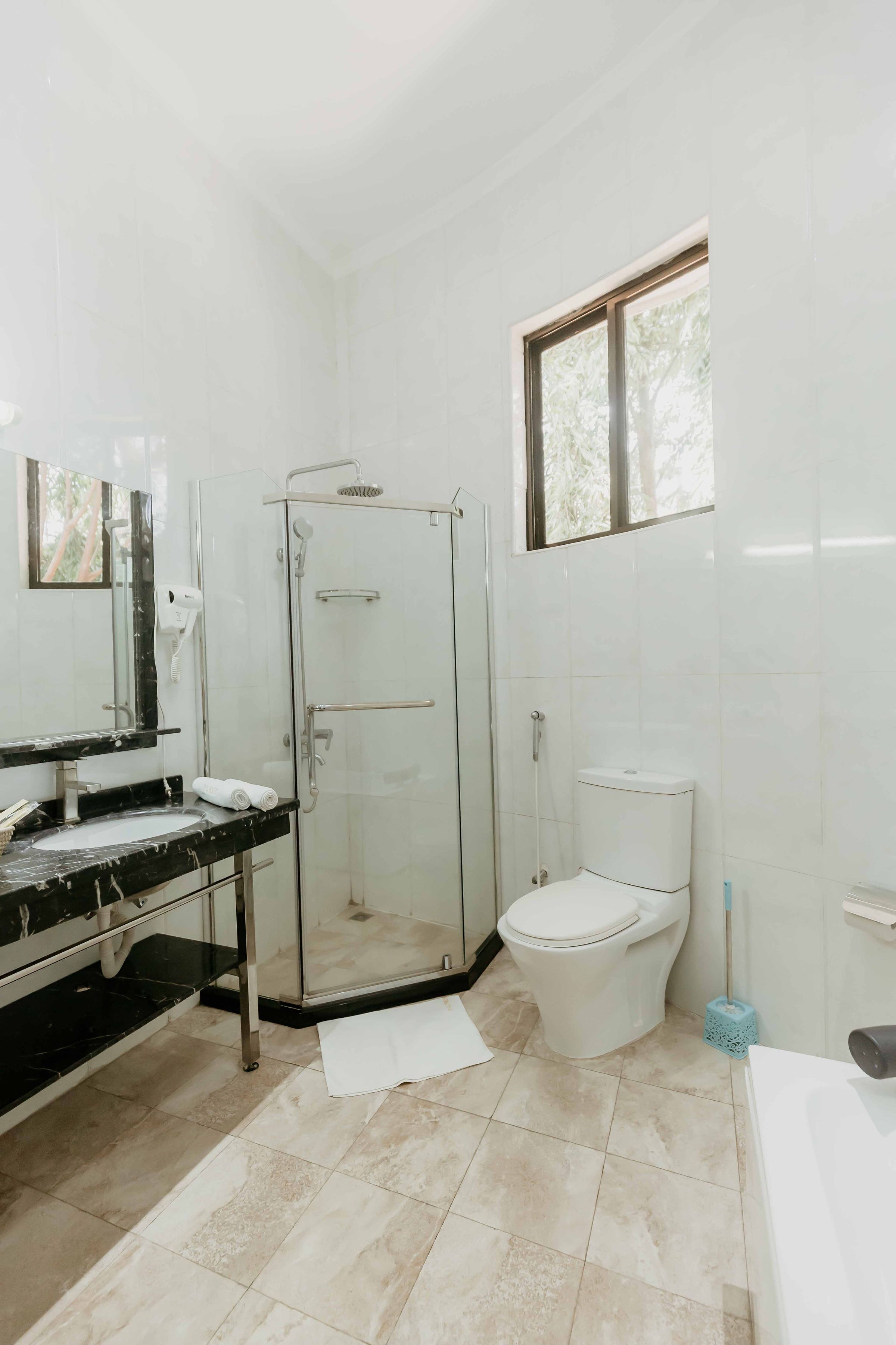 A bathroom with a glass-enclosed shower, a toilet, and a sink with a mirror.