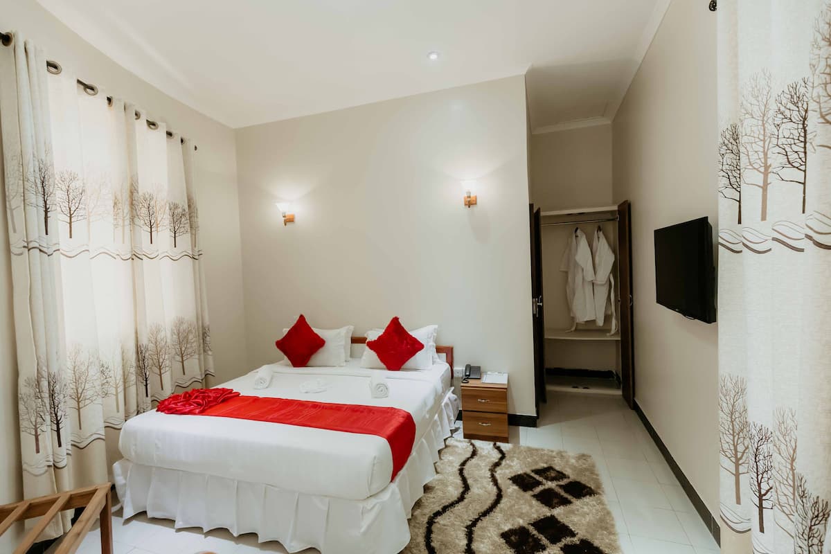 Une chambre d’hôtel avec un grand lit, deux tables de chevet, une télévision et une armoire.
