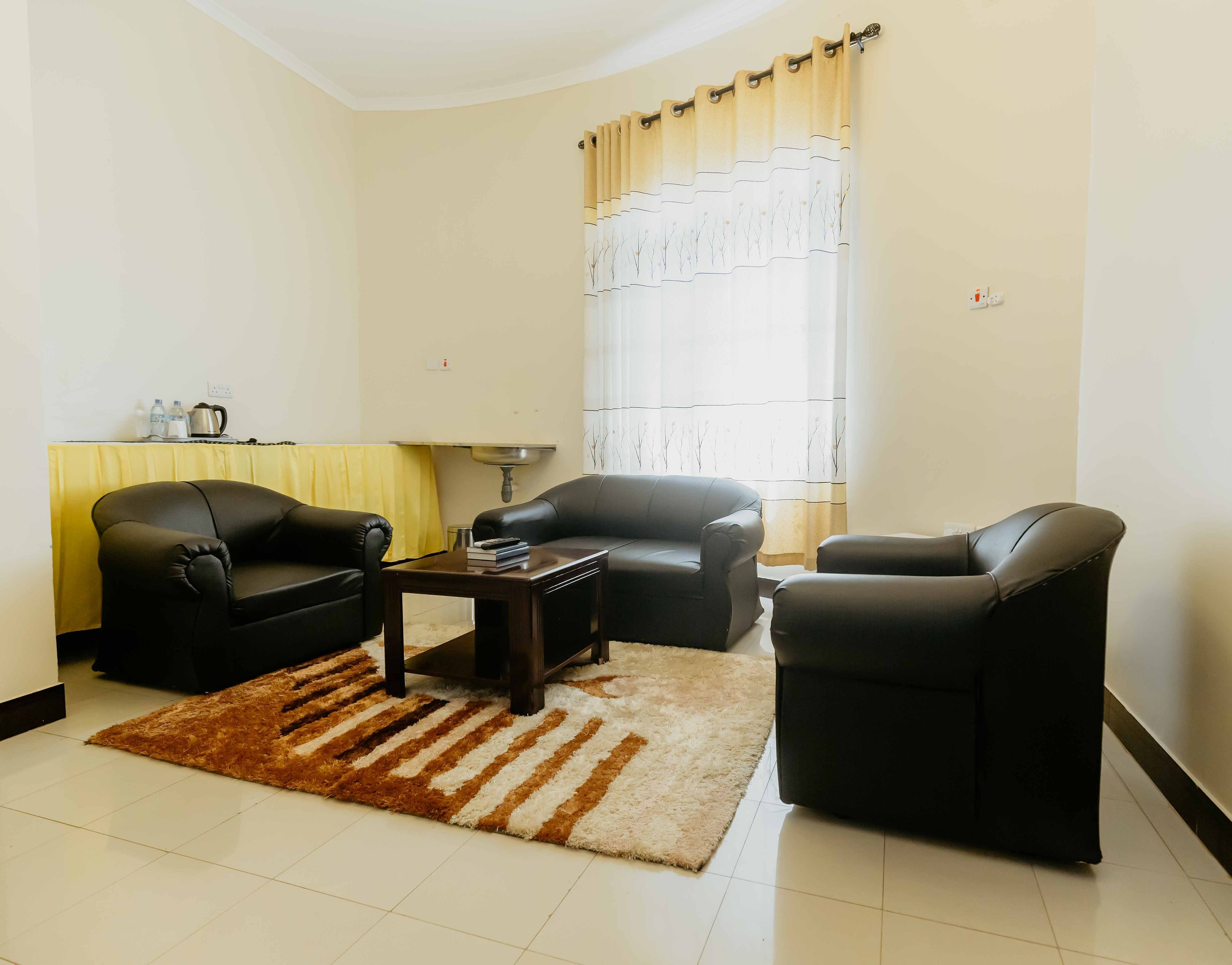 A living room with two black leather sofas, a coffee table, and a patterned rug.
