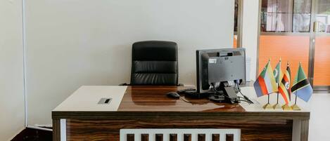 Un mostrador de recepción con un monitor de computadora, una silla y una exhibición de banderas.