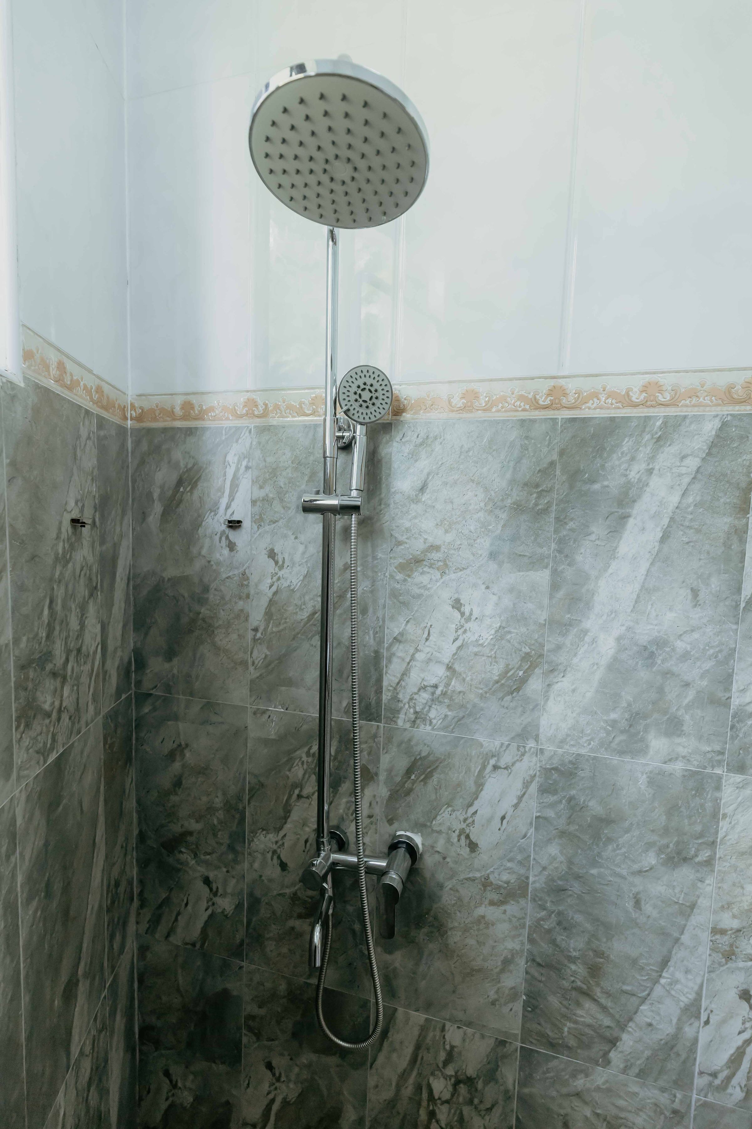 A shower with a handheld showerhead and a wall-mounted faucet.