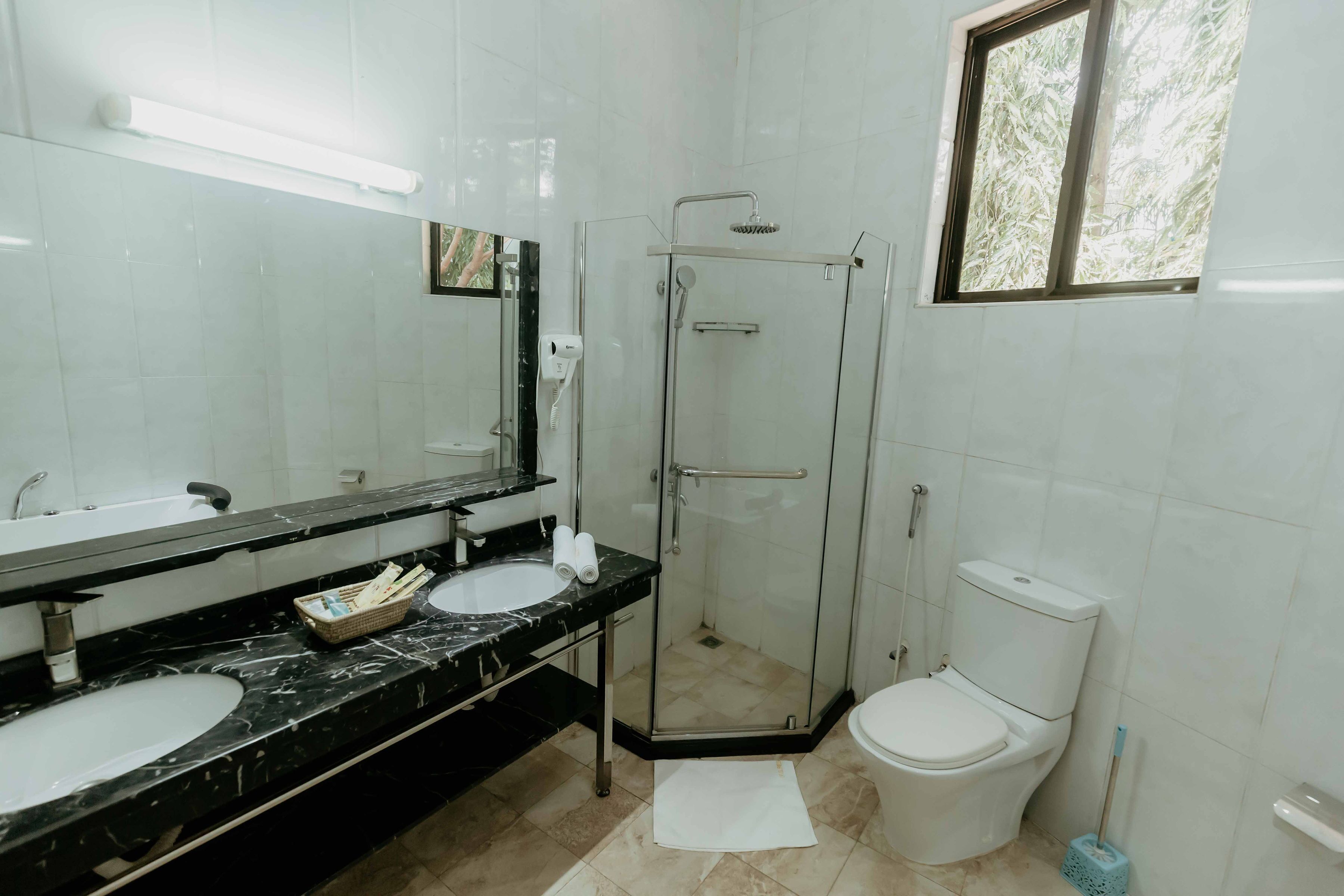Une salle de bain avec deux lavabos, une douche à parois de verre et des toilettes.