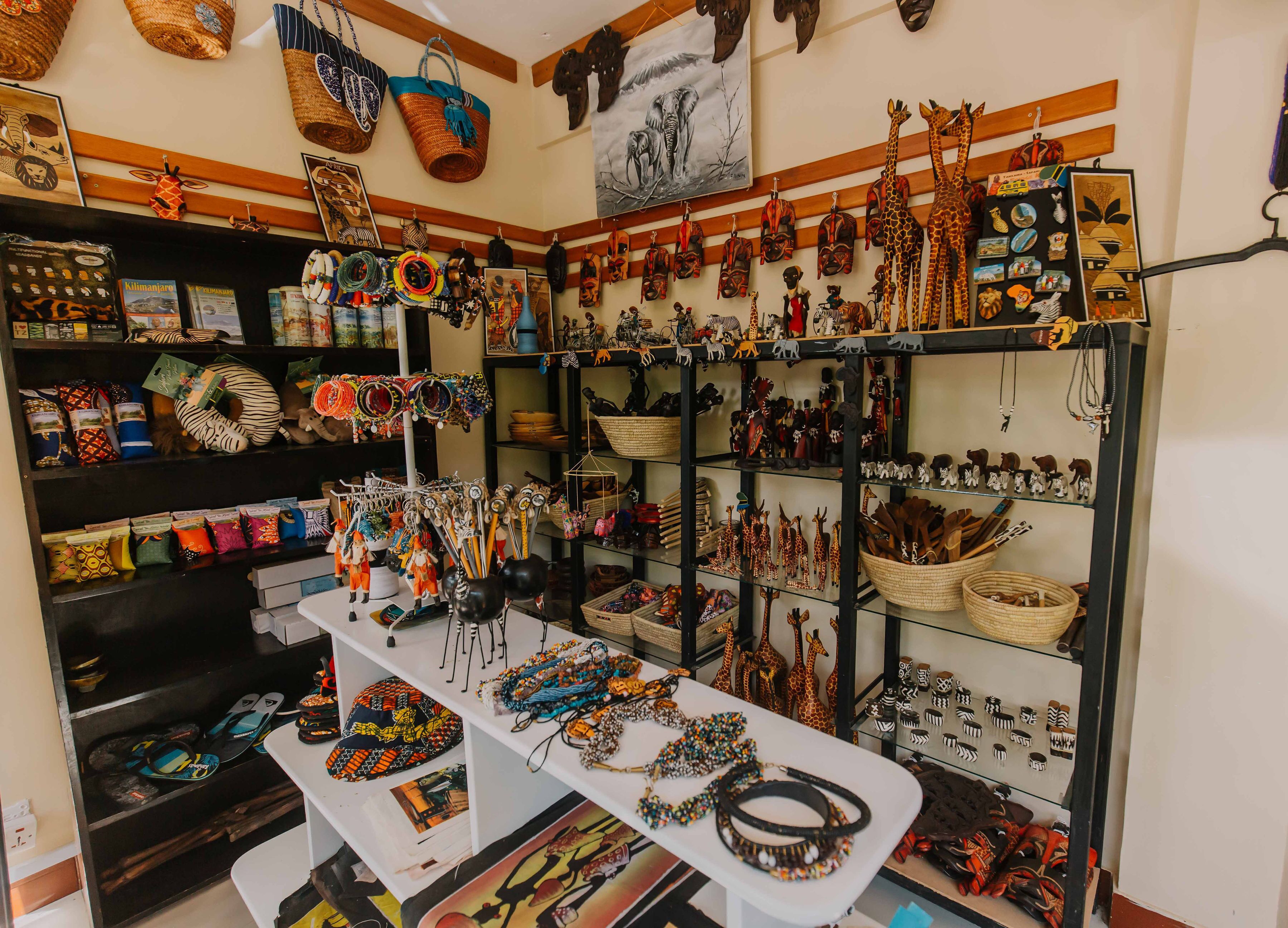 Une pièce où l’on trouve des étagères exposant divers articles, notamment des sacs, des chapeaux et des bijoux.