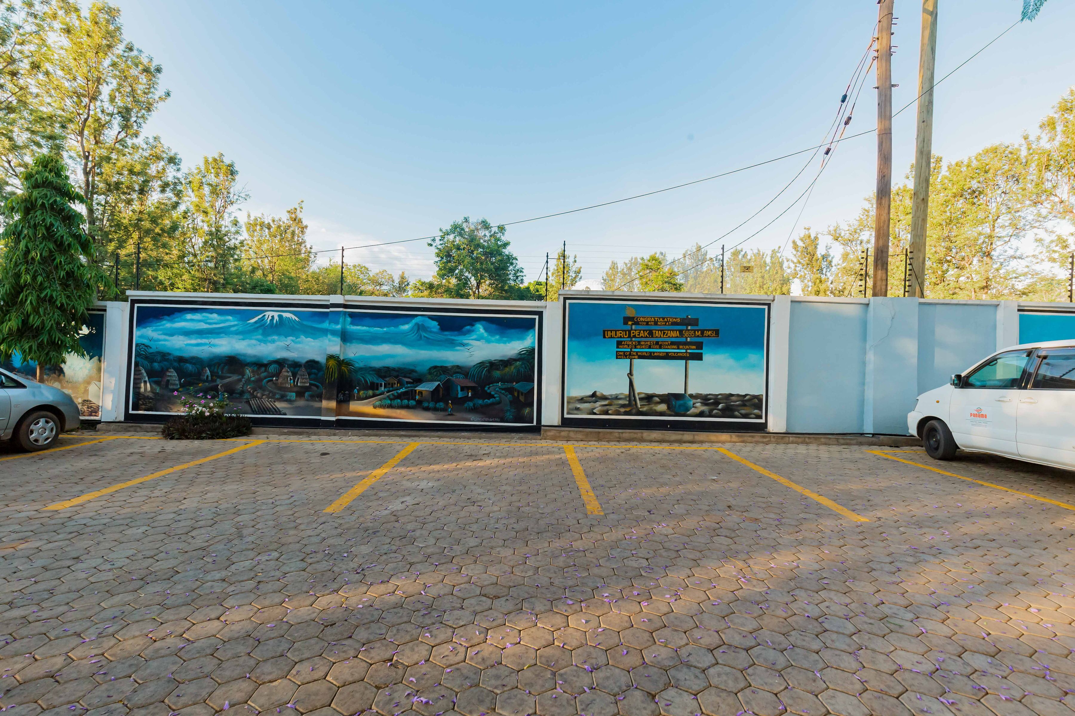 A parking area with hexagonal tiles and a mural depicting a landscape with a mountain and trees.