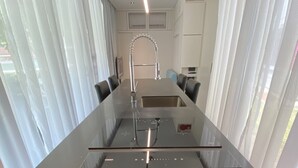 A modern kitchen with a central island, stainless steel appliances, and a sleek faucet. - Shipping Container Hotel @ One-North (Singapore)