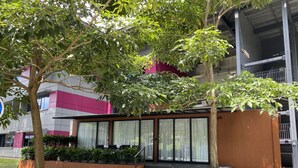 A modern building with a glass facade, a small outdoor seating area with plants, and a staircase leading to the entrance. - Shipping Container Hotel @ One-North (Singapore)