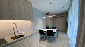 A modern kitchen with a built-in sink, a dining area with a table and chairs, and a light-colored floor. - Shipping Container Hotel @ One-North (Singapore)
