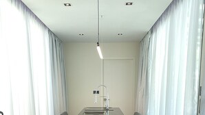 A conference room with a long table, black chairs, a modern faucet, and white curtains. - Shipping Container Hotel @ One-North (Singapore)
