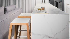 A modern kitchen with a marble countertop, wooden stools, and pendant lighting. - Elysium Boutique Apartments (Zografos)