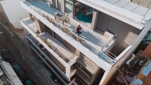 A multi-story building with a balcony, outdoor seating, and a view of the street below. - Elysium Boutique Apartments (Zografos)