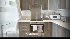 Une cuisine moderne avec des meubles en bois, un réfrigérateur en acier inoxydable, un four à micro-ondes et un grille-pain.
