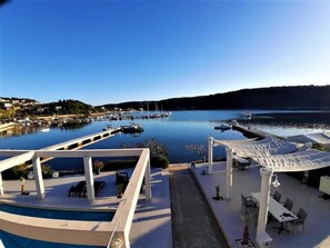 A marina with boats, a pool, and outdoor seating areas. - Guesthouse Raffaello (Kampor)