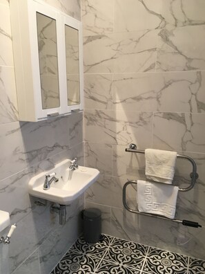 Bathroom features a pedestal sink, mirror, and towel rack.