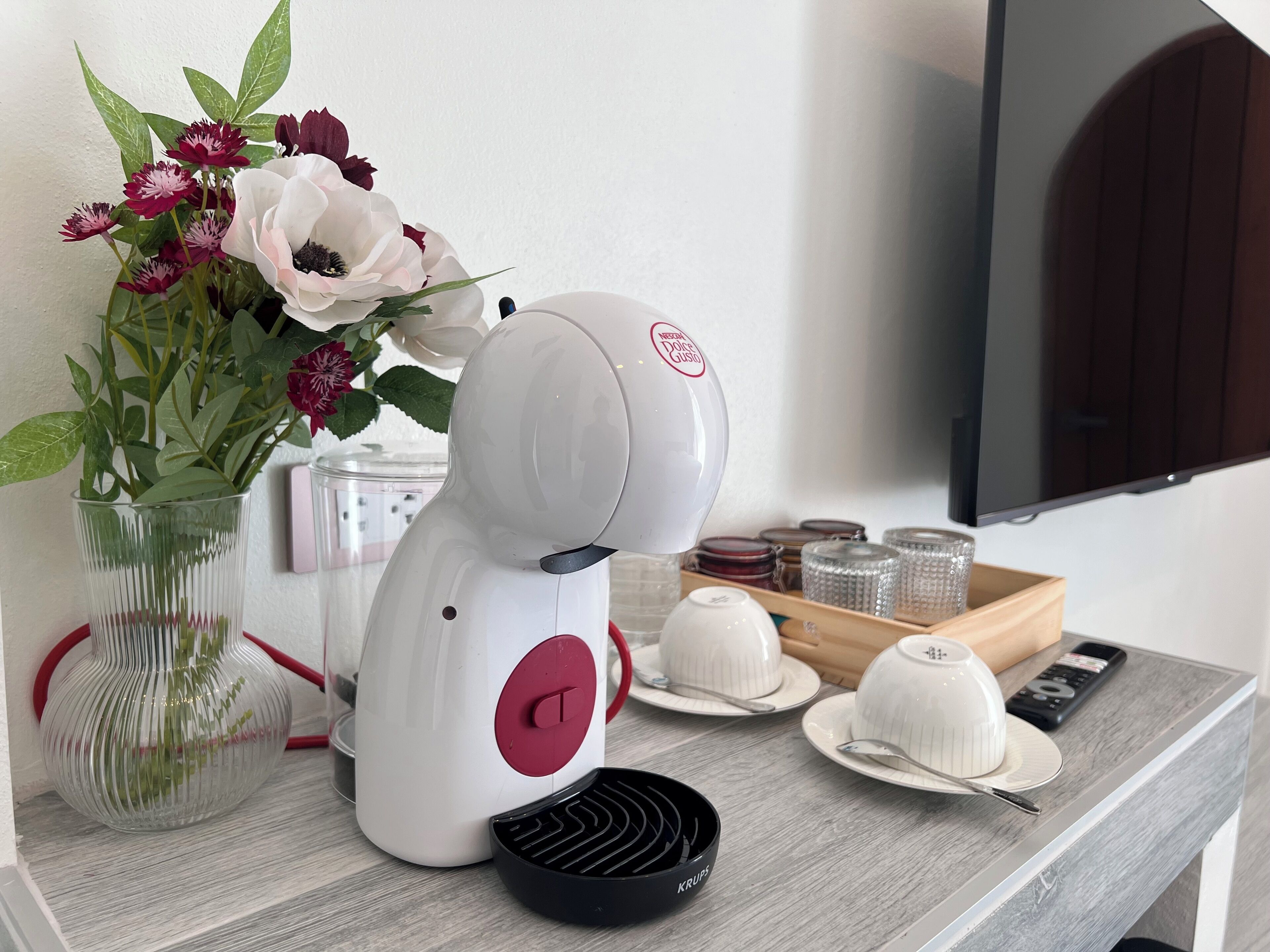 A kitchen area with a white appliance, a vase with flowers, and a tray with dishes.