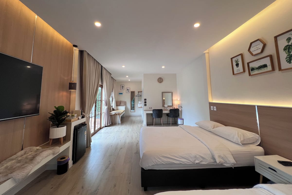 Quarto de hotel moderno com uma cama grande, uma escrivaninha com cadeira, televisão e uma pequena cozinha.