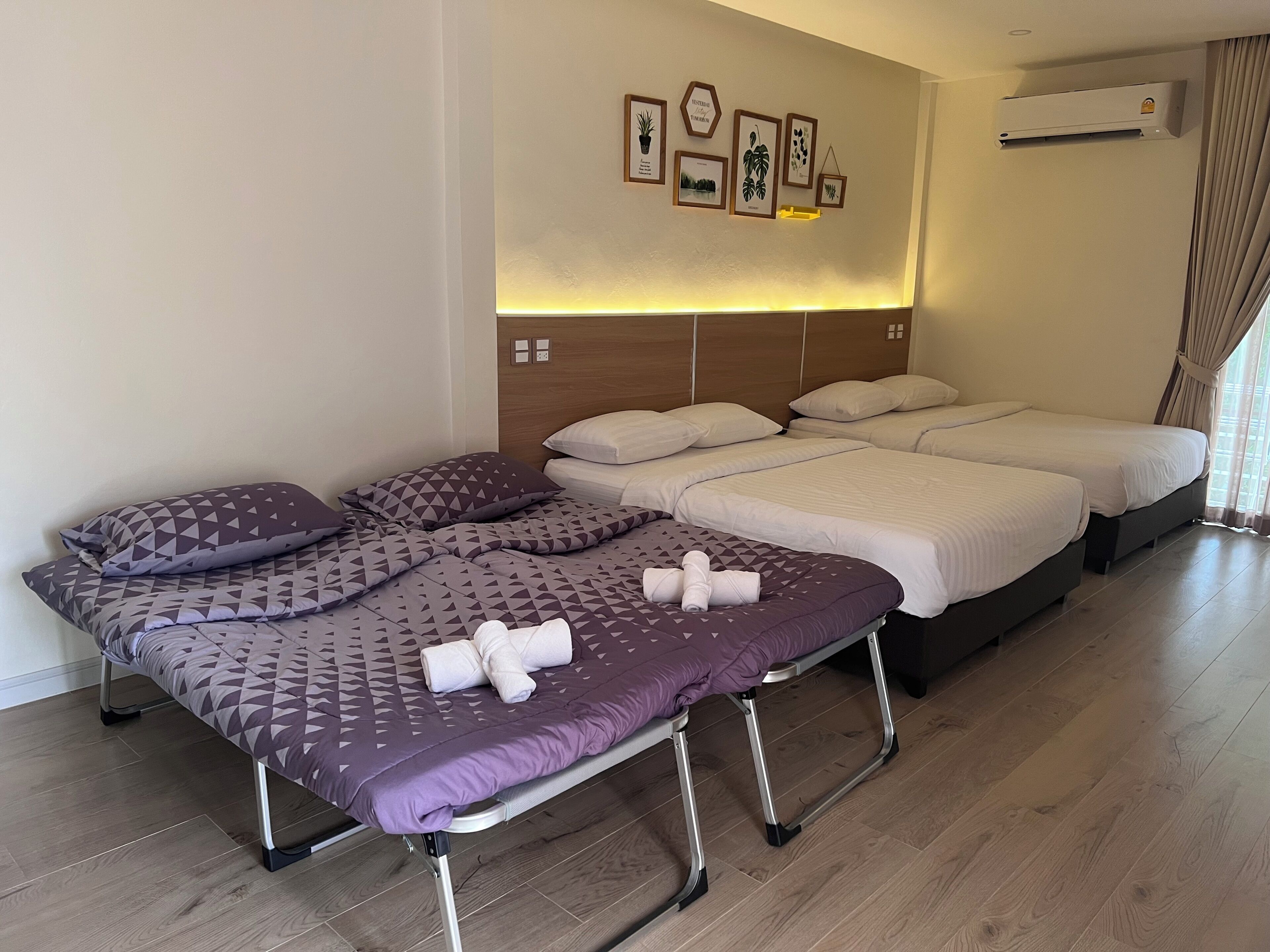 A hotel room with a bed, two bedside tables, a wall-mounted air conditioner, and a window with curtains.