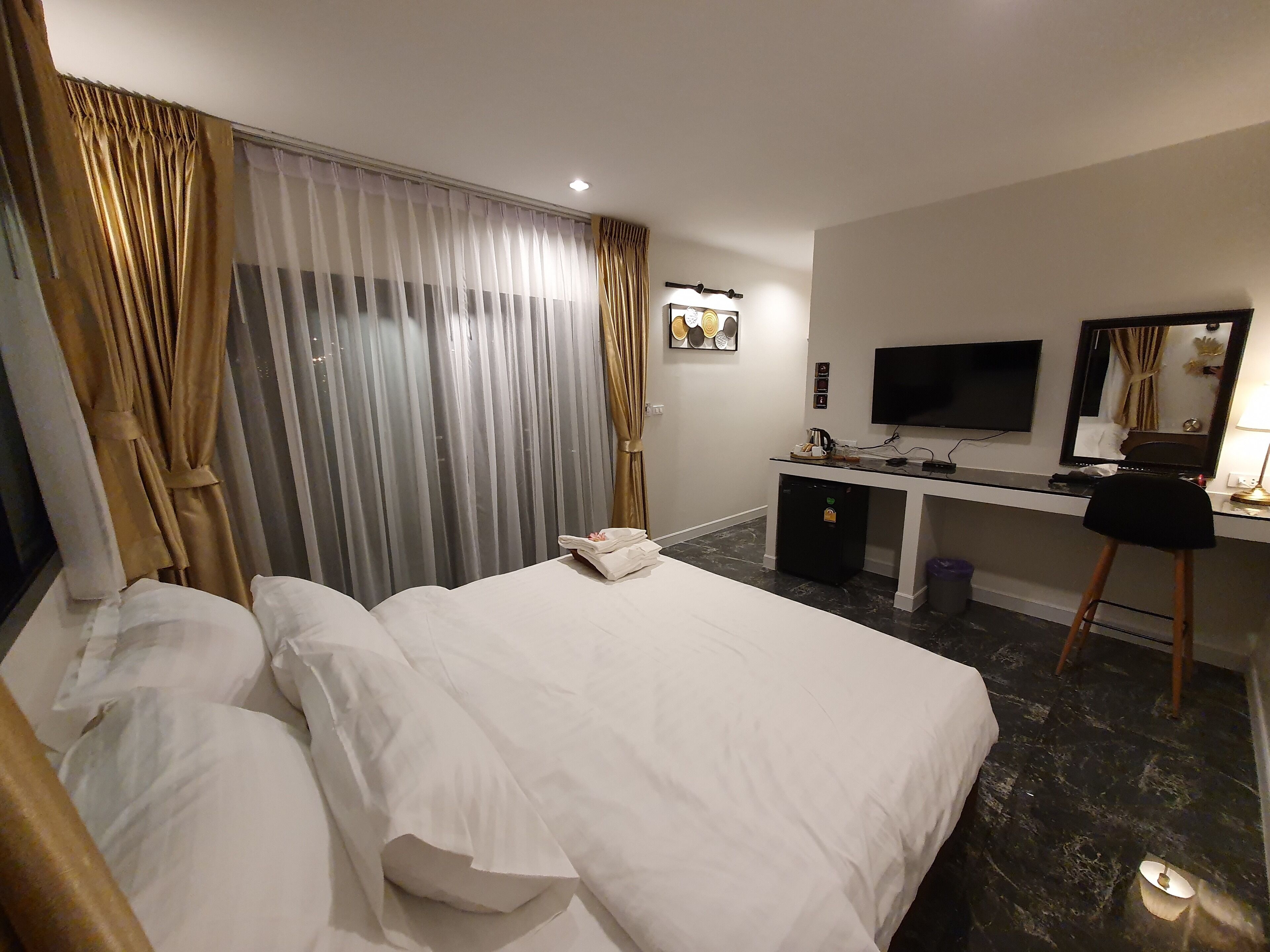 A hotel room with a bed, a desk, a television, and a mirror.