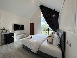 A modern bedroom with a bed, a TV, a small fridge, and a window with curtains.