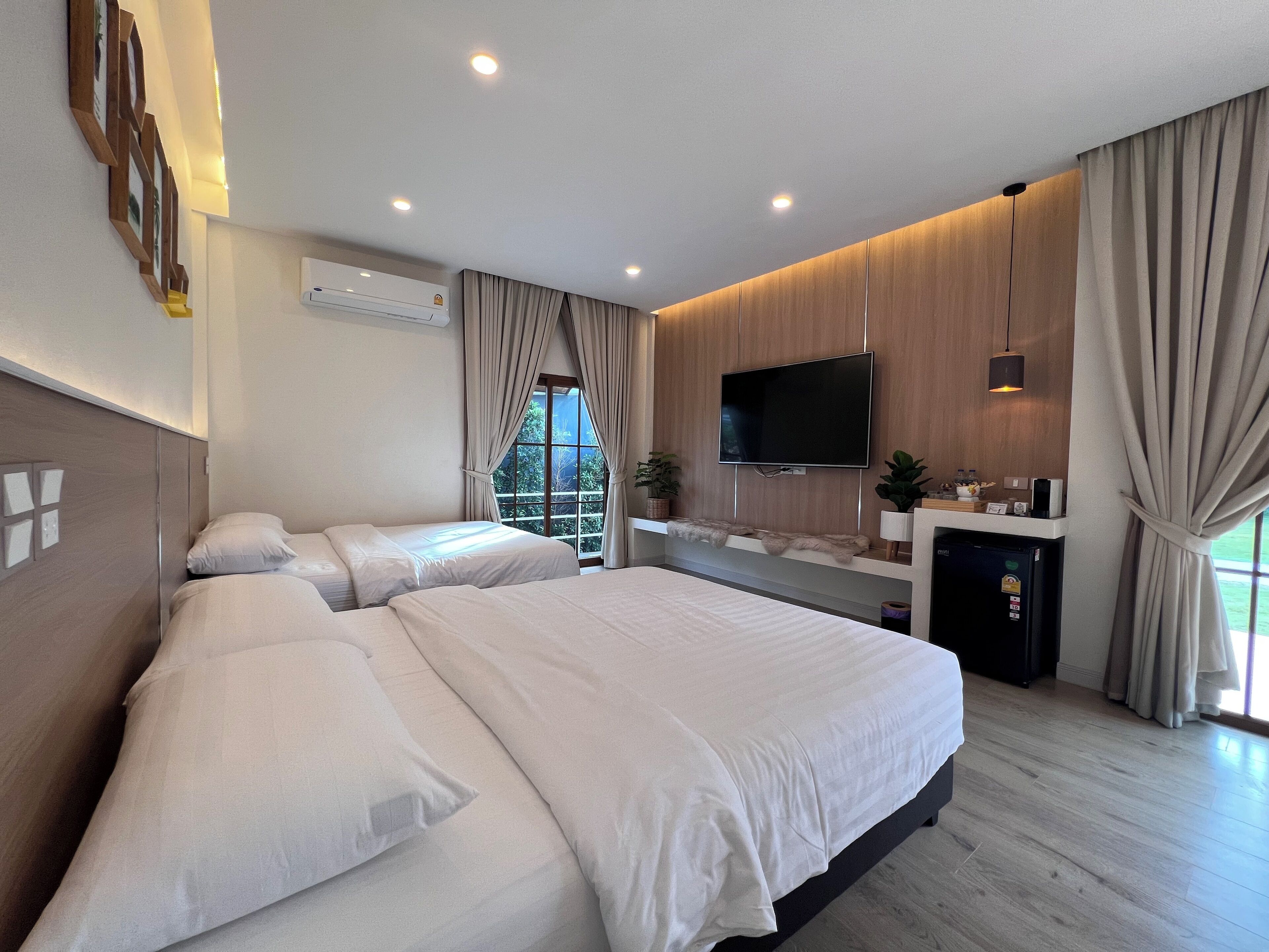 Een moderne hotelkamer met een groot bed, een flatscreen televisie, een klein bureau en een groot raam met gordijnen.