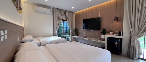 Een moderne hotelkamer met een groot bed, een flatscreen televisie, een klein bureau en een groot raam met gordijnen.