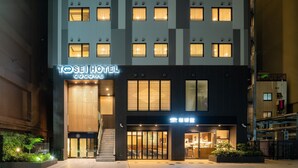 A modern hotel with a prominent entrance, a visible staircase, and a well-lit facade.