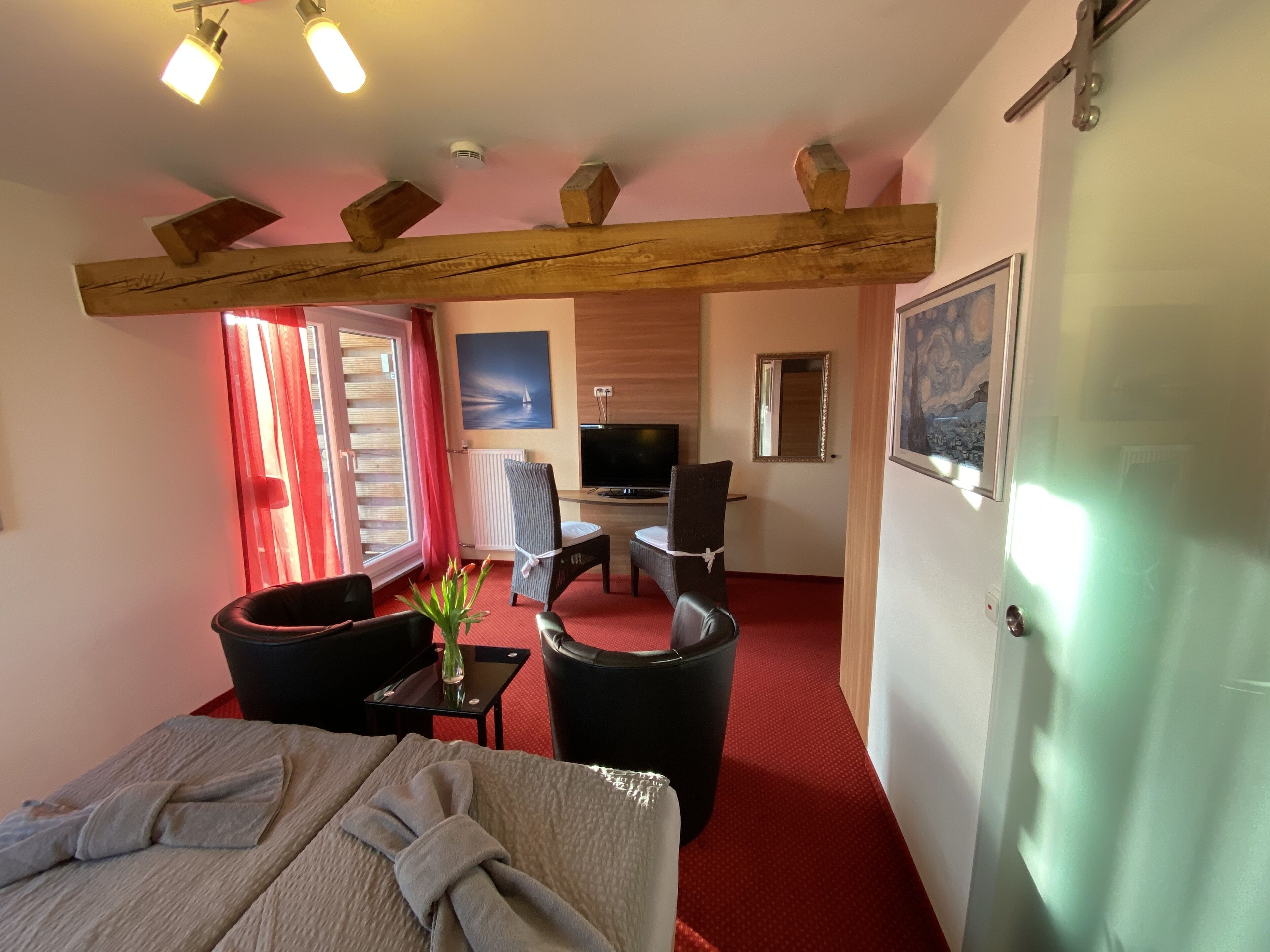 Een hotelkamer met een bed, een bureau, een stoel, een televisie en een schilderij aan de muur.