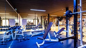 A gym with weightlifting equipment, benches, and dumbbells.