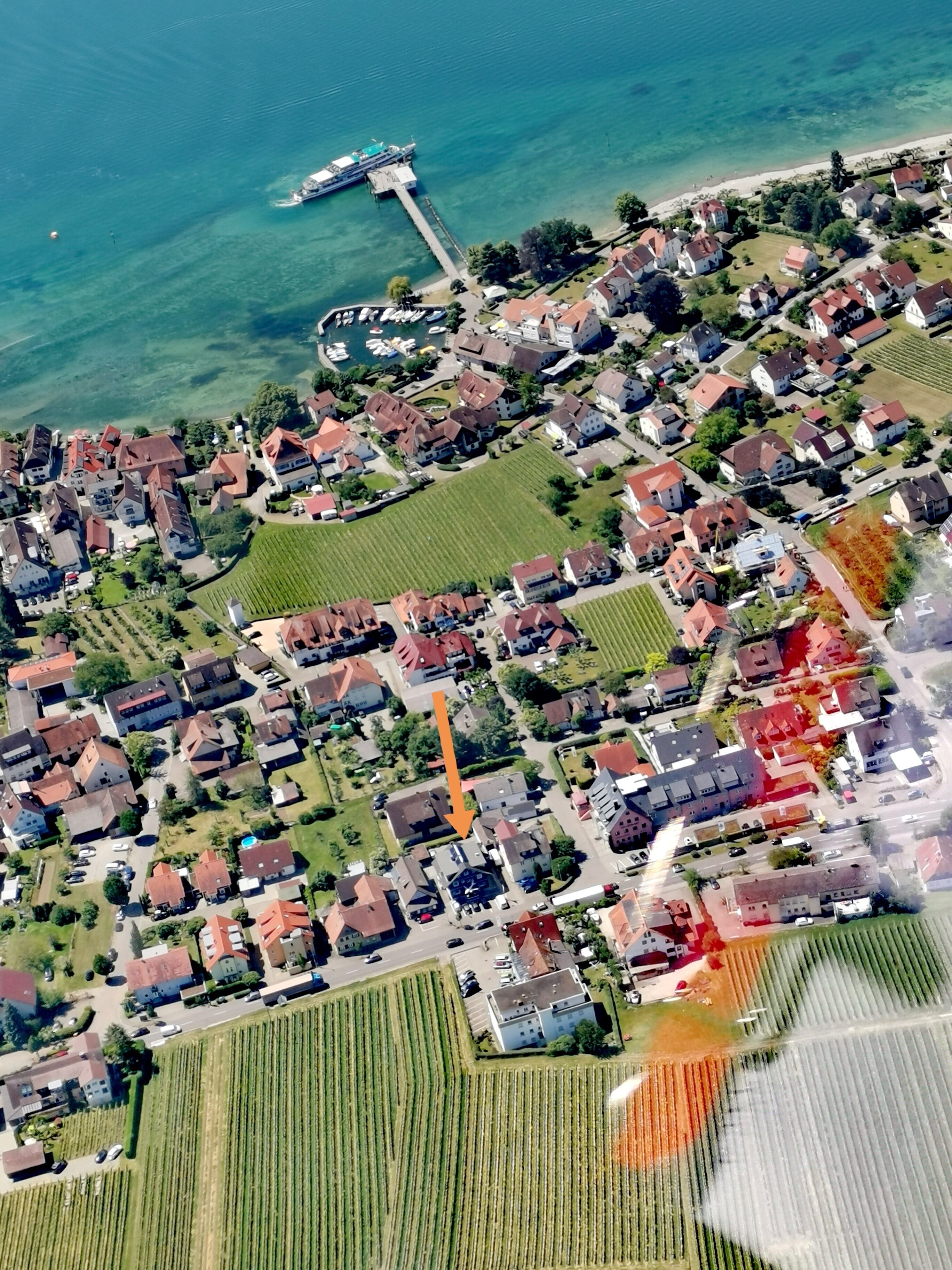 Luftaufnahme einer Küstenstadt mit Wohngebäuden, einem Steg und einem Yachthafen.