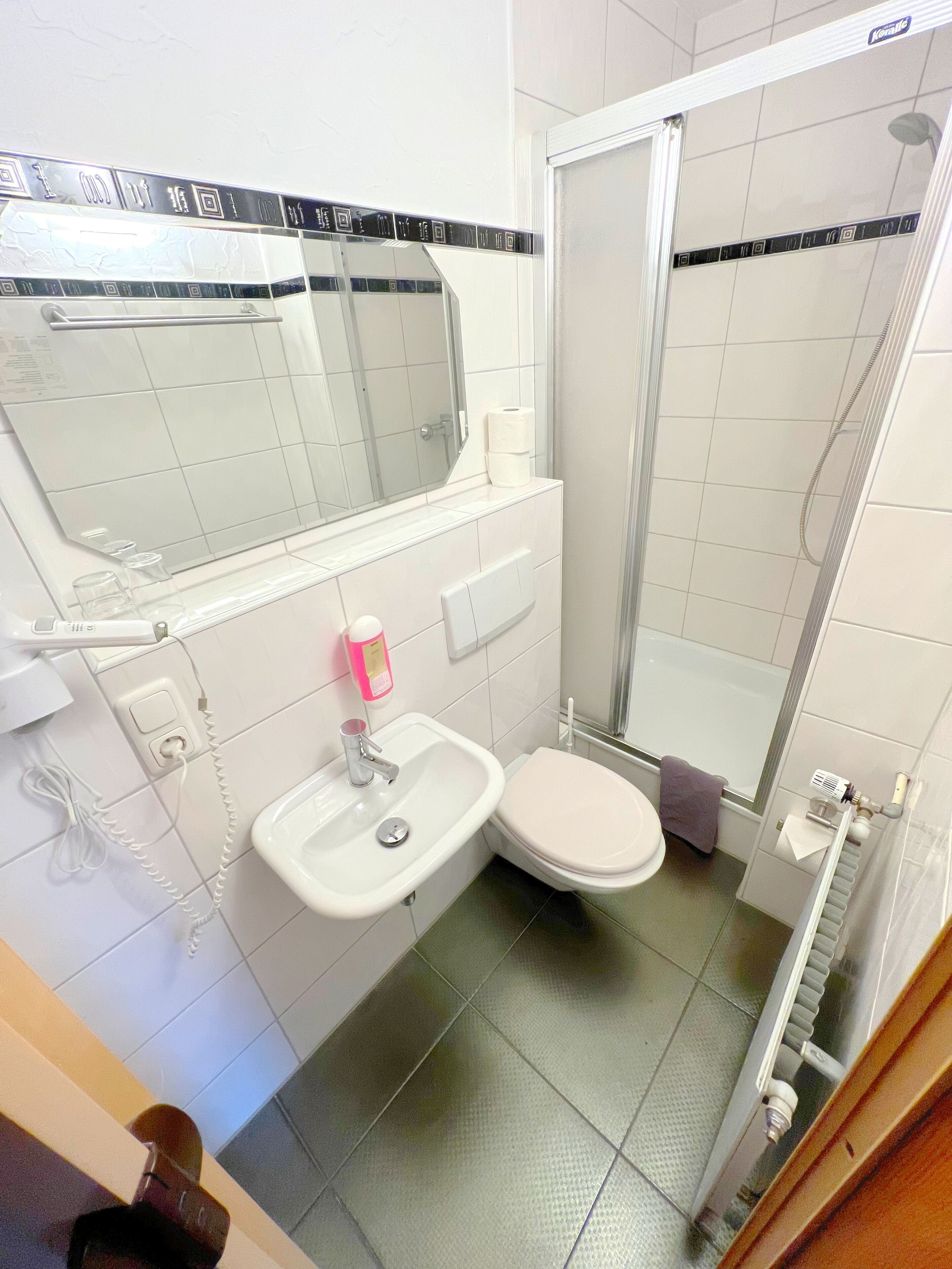 Un bagno con lavandino, WC, specchio e doccia.