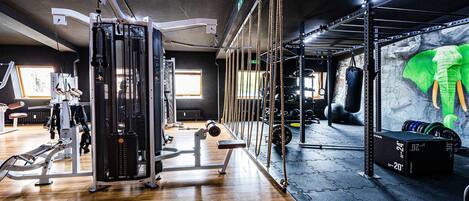 Ein Fitnessraum mit verschiedenen Trainingsgeräten, darunter ein Kabelzug, eine Gewichtbank und eine Klimmzugstange.