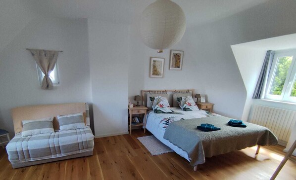 Un dormitorio con cama, sofá, mesita de noche y ventana.