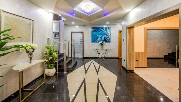 Eine moderne Lobby mit Marmorboden, einer Treppe, einem Empfangsbereich und einem großen abstrakten Gemälde.
