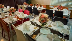 Ein Restaurant mit mehreren für das Essen gedeckten Tischen, jeweils mit weißen Tischdecken, ordentlich drapiertem Besteck und floralen Mittelpunkten.