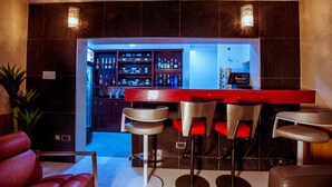 Eine Bar mit rotem Tresen, mehreren Barhocker und einer gut sortierten Bar.