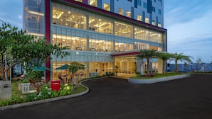 A modern hotel with a glass facade, outdoor seating, and a landscaped entrance.