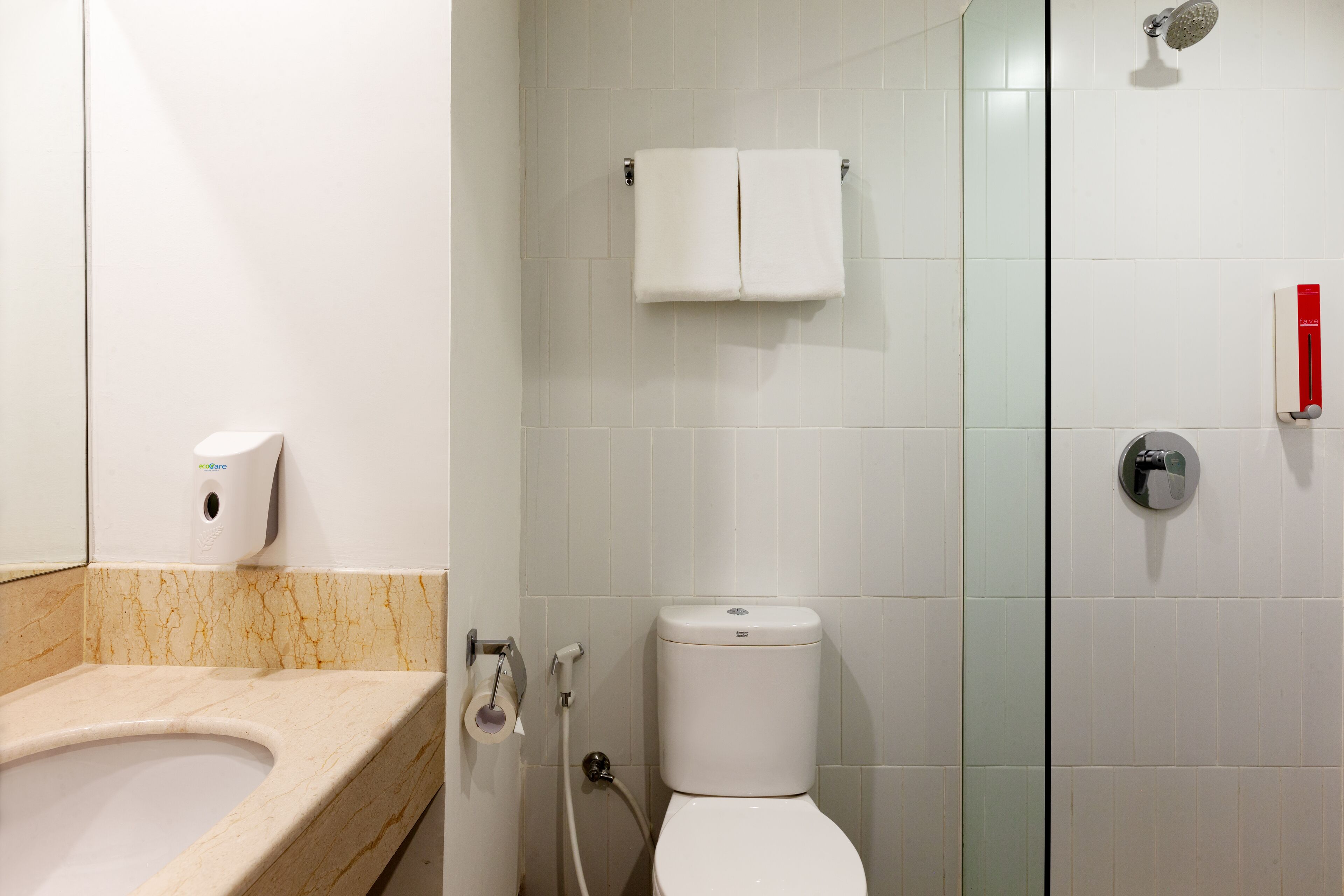 A bathroom with a toilet, a sink, a glass shower enclosure, and a towel rack.