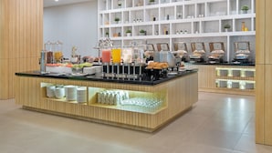 A modern breakfast bar with a variety of food options, including fruits, pastries, and beverages.