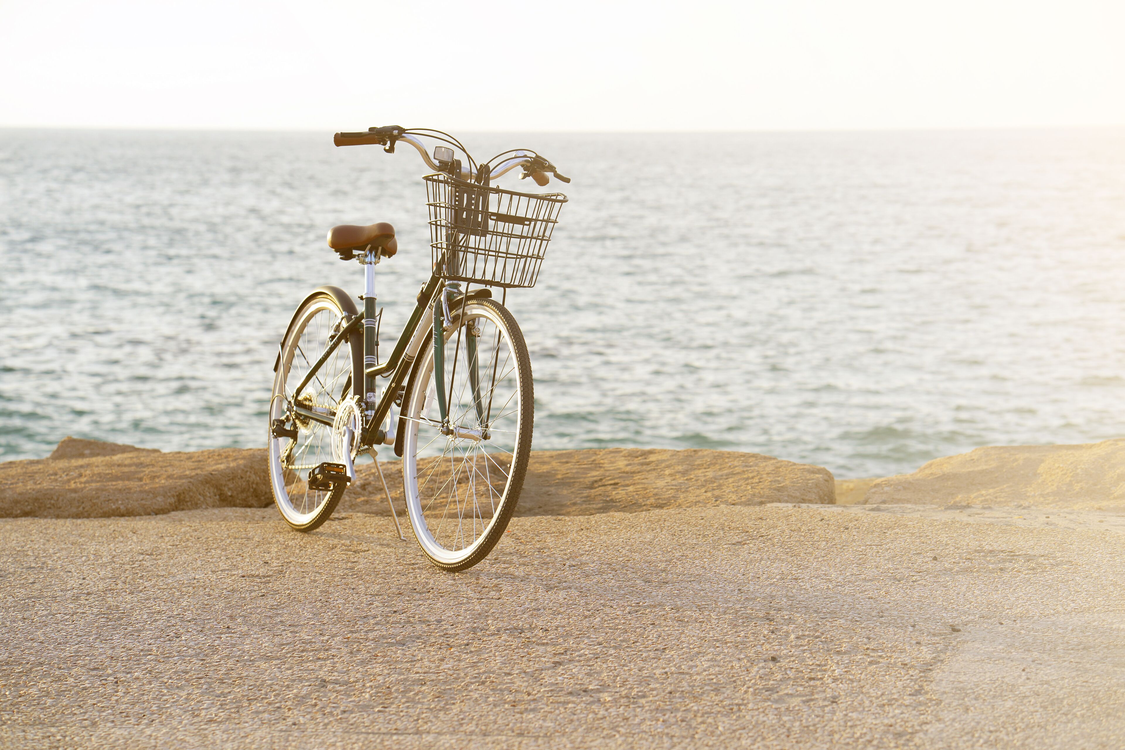 Un vélo avec un panier, sur une plage rocheuse, avec l’océan en arrière-plan.